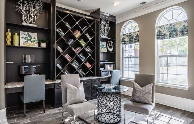 a living room with chairs and a table and a book shelf