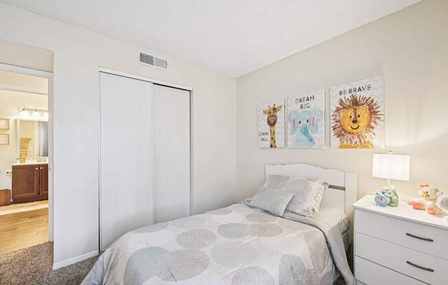 A bedroom with a bed, nightstand, and a wall hanging with the words "Dream Big, Be Brave" on it.