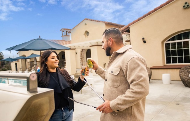 a man giving a woman a bottle of beer outside of a house