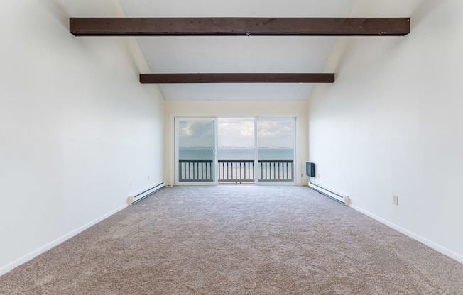 an empty room with white walls and a large window with a view of the ocean