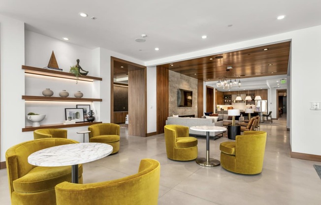 the lobby of a hotel with yellow chairs and tables at The Colony, Charlotte, NC, 28211