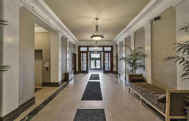 a hallway with a bench and plants and a chandelier at The Knights @ 506 Delaware Apartments, New York