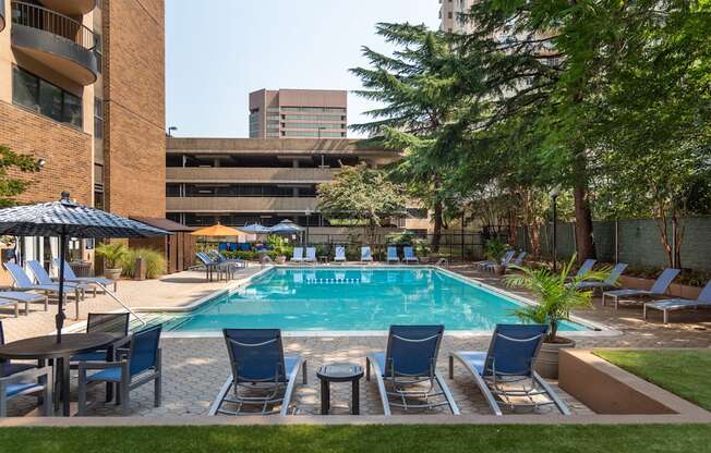 a swimming pool with blue chairs and a building in the background