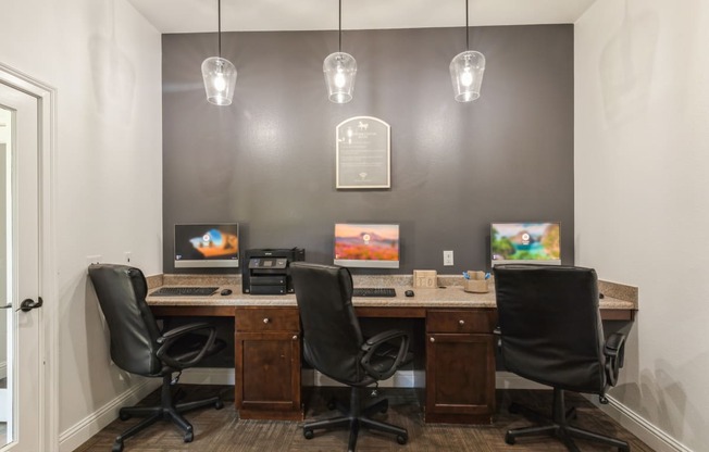 two desks with chairs in a room with two computer monitors