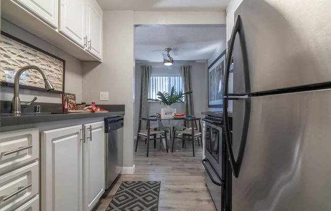 a kitchen and dining room with stainless steel appliances and white cabinets at Sunnyvale Crossings Apartments, LLC, Sunnyvale