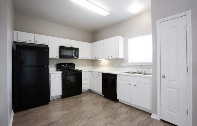 A kitchen with black appliances and white cabinets.