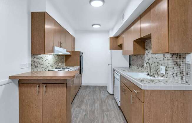 A kitchen with wooden cabinets and a tiled backsplash at The Phoenix Apartments on 6th Avenue, Phoenix, AZ