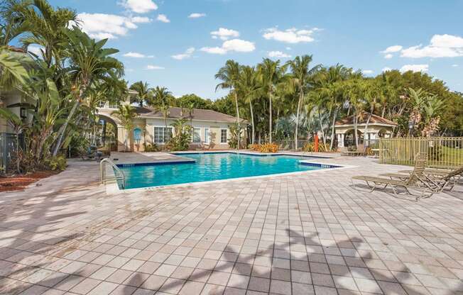 A pool surrounded by a tiled patio and palm trees.