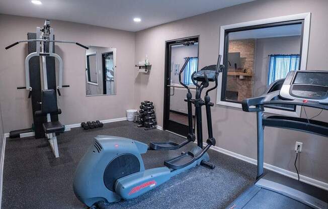 A home gym with a treadmill, elliptical trainer, and a stationary bike.