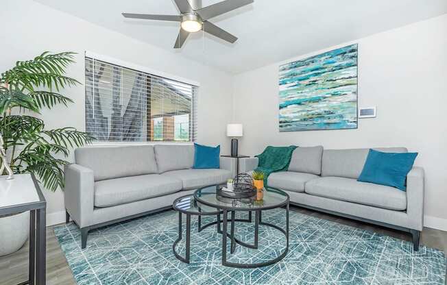 A living room with a grey couch, a coffee table, and a ceiling fan.