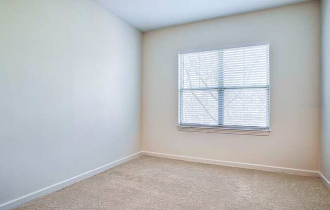 a bedroom with white walls and a window