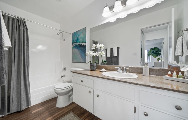 a bathroom with white cabinets and a gray shower curtain