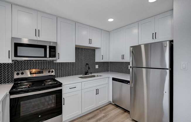 A modern kitchen with a stove, microwave, and refrigerator.