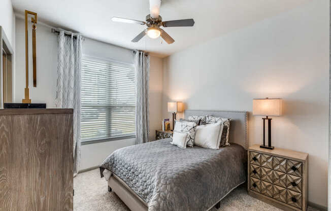 A bedroom with a bed, nightstand, and a ceiling fan.