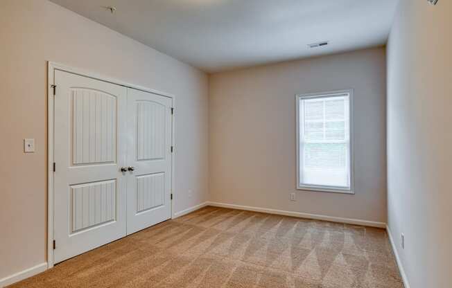 an empty living room with two doors and a window