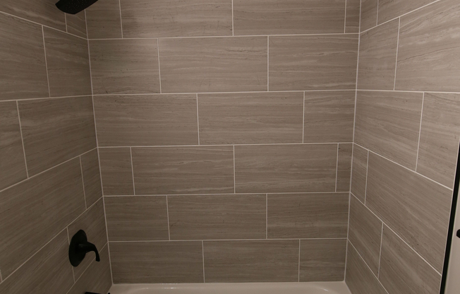 Elegant bathroom showcasing a modern bathtub with sleek tile surround and matte black fixtures.