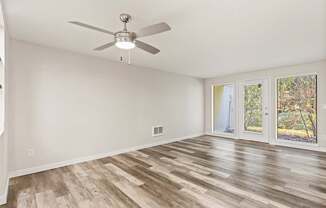 A room with a ceiling fan and wood flooring.