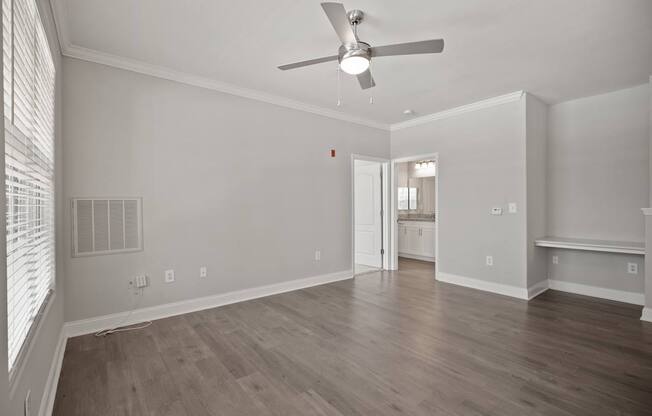 A room with a ceiling fan and wooden flooring.