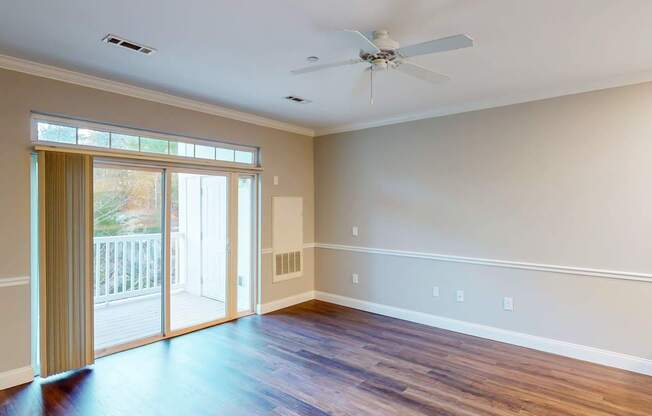 A room with a ceiling fan and sliding glass doors.