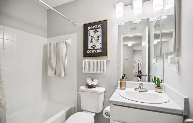 A bathroom with a white toilet, sink, and a poster on the wall.