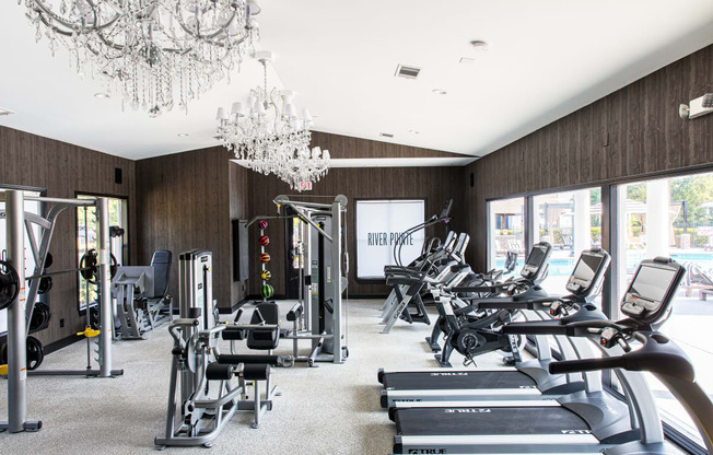 a gym with cardio machines and chandeliers