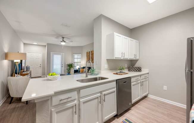 an open kitchen and living room with white cabinets and a white counter top