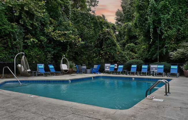 A pool surrounded by trees and chairs.at Lofts of Wilmington, North Carolina, 28405