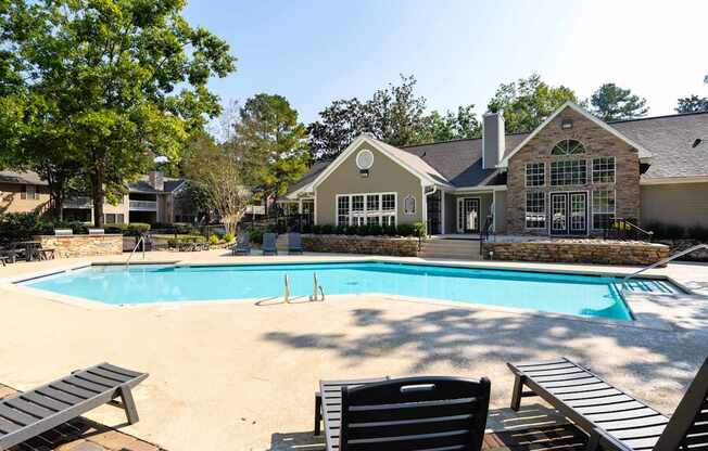 A pool with a bench and a house in the background.