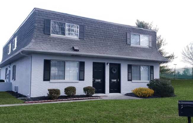 a white house with black shutters and a lawn