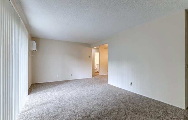 an empty living room with white walls and carpet