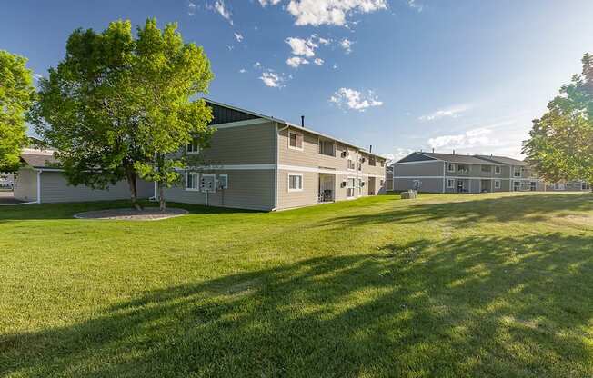 Row of apartments in Billings, MT with a large grass field and trees surrounding buildings