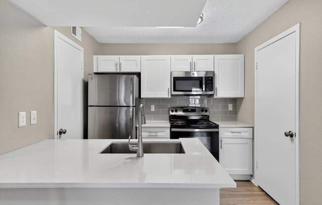 A kitchen with a white countertop and stainless steel appliances.