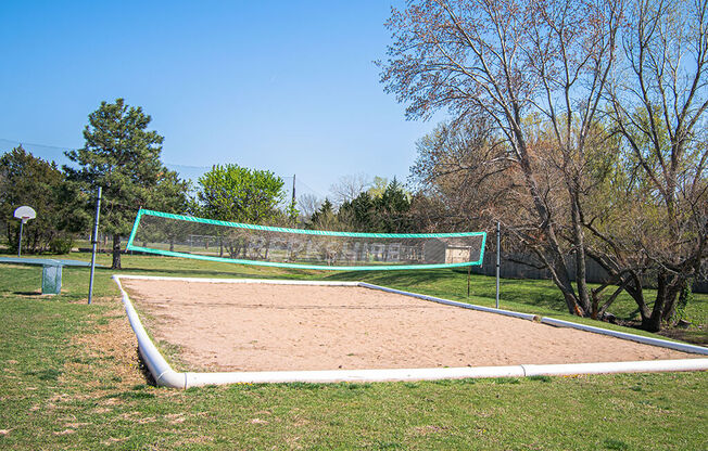 A sand volleyball court with a green net and white boundary lines.