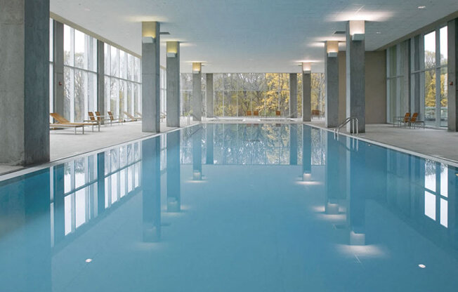 A large indoor swimming pool with a reflective surface and a sunny day outside.