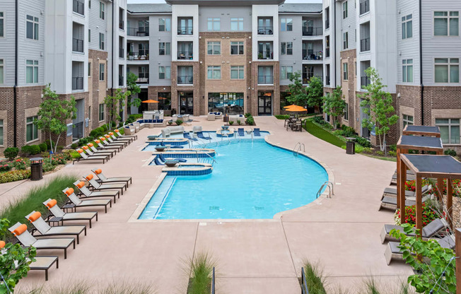 an outdoor pool with lounge chairs and an apartment building