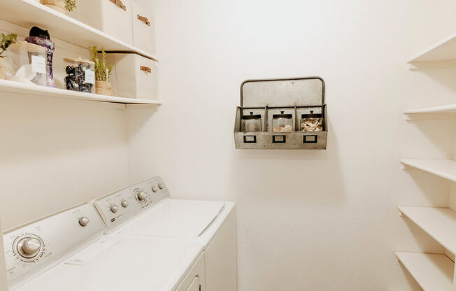 A white washing machine in a laundry room with shelves and storage.