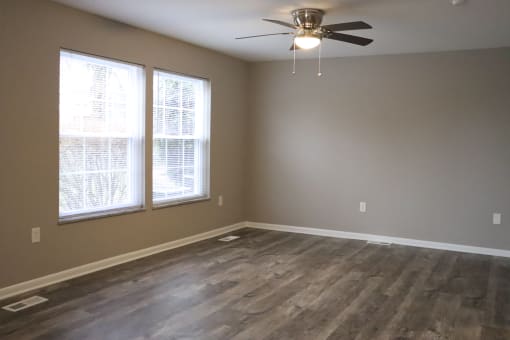 an empty living room with wood floors and a ceiling fan