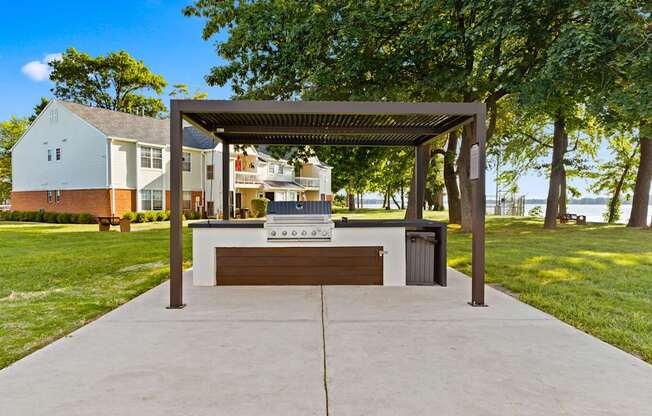 A pavement leads to a pavilion with a bench and a table underneath it.