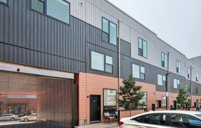 A modern building with a black and pink facade and a car parked in front.