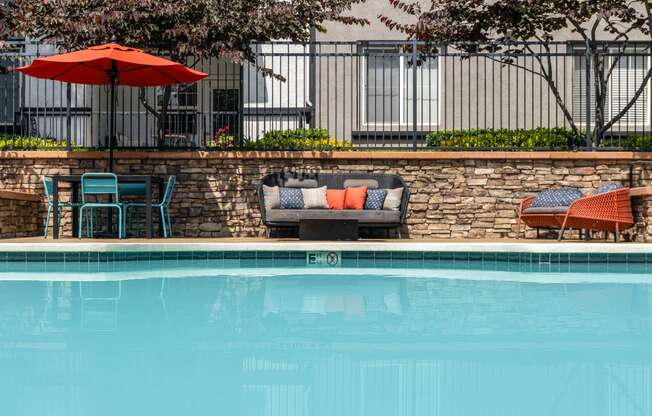 a swimming pool with chairs and an umbrella next to a hotel pool