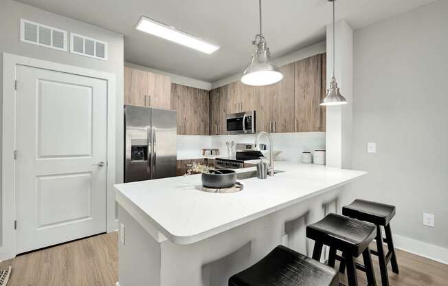 A kitchen with a white countertop and black stools at The Ashton at East Park Apartments, Kennesaw, GA, 30144