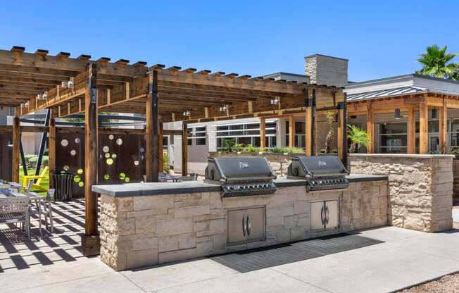 an outdoor kitchen with a barbecue and a pergola