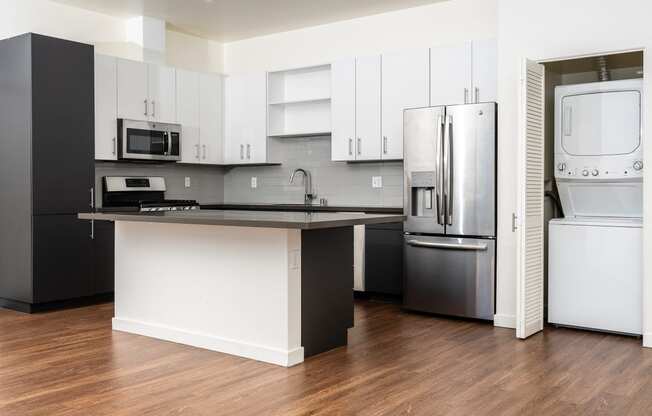 kitchen with stainless appliances, white cabinets, stackable washer and dryer