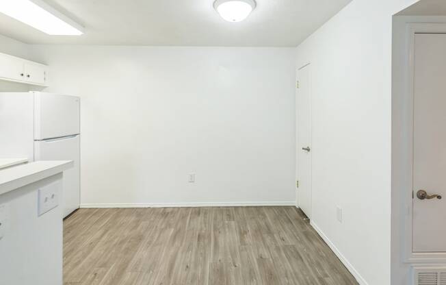 an empty room with white walls and a white refrigerator