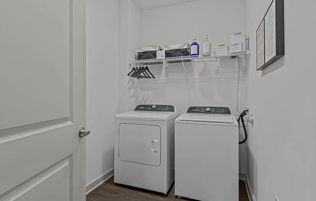 A laundry room with two washing machines and a shelf above them.