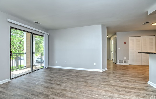 an empty living room with sliding glass doors to a balcony