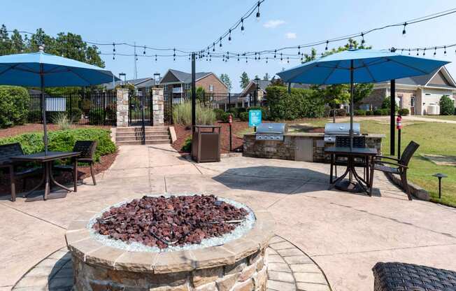 a patio with umbrellas and tables and a fire pit