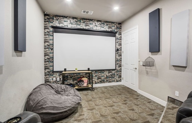 a theater room with a large screen tv and a projector screen on the wall