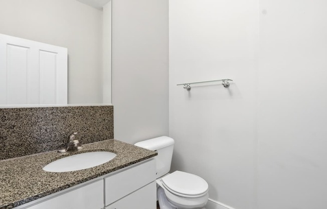 A bathroom with a toilet, sink, and mirror.