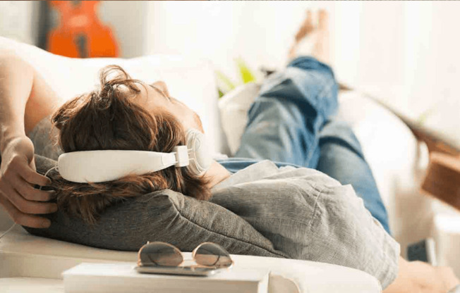 a man laying on a couch wearing a pair of headphones